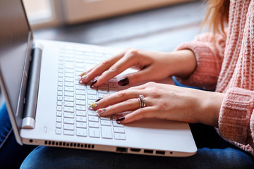 White woman's hands with manicure on the laptop keyboard. Working or studying at home. Freelancer, remote worker, student. Studying online. 