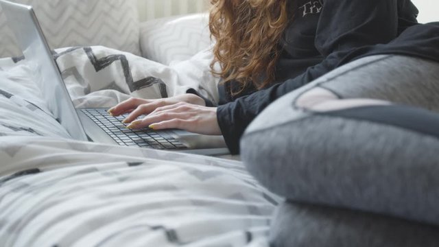 Female professional casually working from home on a bed