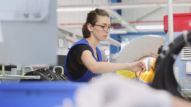 girl worker on a special machine twists the wiring for modern cars