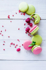 Sweet colorful French macaroons cookies dessert on white wooden background.The composition is decorated with raspberries, mint leaves.copy space.Greeting card for mother's day, holiday, birthday.