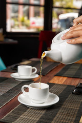 pour tea from a teapot into a cup