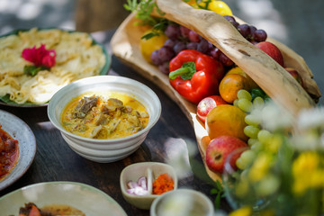 Goat curry is served in a ceramic bowl on a wooden table during a garden party.