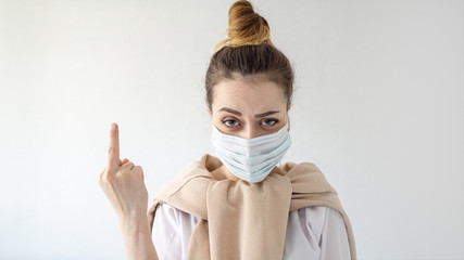 Young beautiful european girl in mask on isolated white background Showing middle finger doing fuck you bad expression, provocation and rude attitude. Coronavirus outbreak or Covid-19