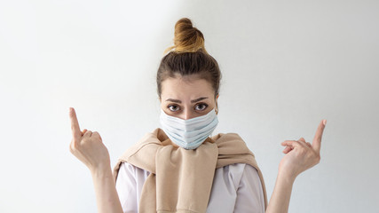 Young beautiful european girl in mask on isolated white background Showing middle finger . Coronavirus outbreak or Covid-19, Concept of Covid-19 quarantine 
