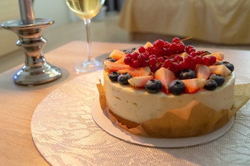 warm-colored fruit cake by the glass of champagne and candles