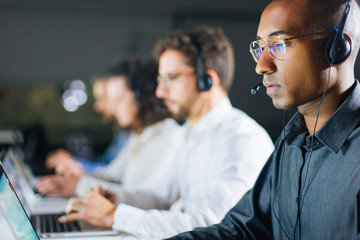 Concentrated African American call center operator working. Thoughtful call center operators during working process. Call center concept