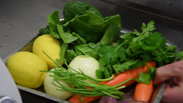bac avec plusieurs l&eacute;gumes frais lav&eacute;s et encore mouill&eacute;s dans une cuisine professionnelle une main prend le bac