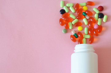 Assorted pharmaceutical medicine pills, tablets and capsules and bottle on pink background. Copy space for text