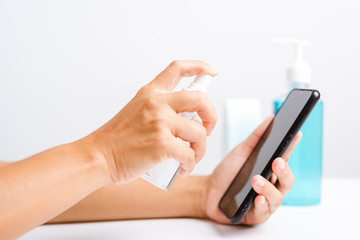 woman applying press dispenser sanitizer alcohol spray squirt to smart mobile phone