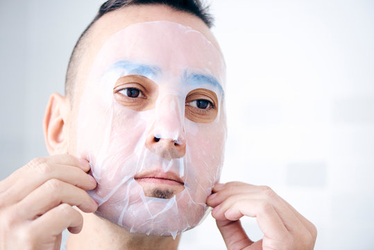 man applying a facial mask to himself