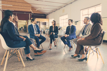 Smiling managers sitting in chairs in circle. Confident office employees talking. Teambuilding concept