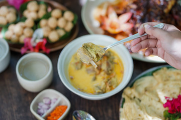 Goat curry is served in a ceramic bowl on a wooden table during a garden party.