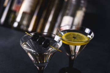 Dry martini with black olives and fresh lemon.Vermouth cocktail inside martini glass over dark...