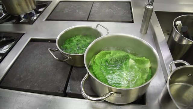 Deux casseroles inox sur des plaques chauffantes de cuisine professionnelle avec un chou qui cuit dans de l'eau  bouillante