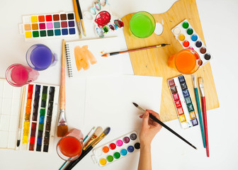 Paints, brushes, and palette on the wood background. The workplace of the artist. Banner for school.