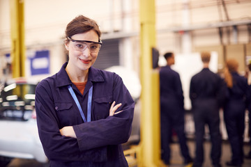 Portrait Of Female Student With Safety Glasses Studying For Auto Mechanic Apprenticeship At College - obrazy, fototapety, plakaty