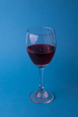 hermosas copas de vino transparentes con vino tinto sobre un fondo azul