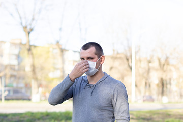 Caucasian man putting on a face medical mask on the street outdoor