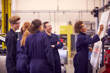 Female Tutor By Whiteboard With Students Teaching Auto Mechanic Apprenticeship At College