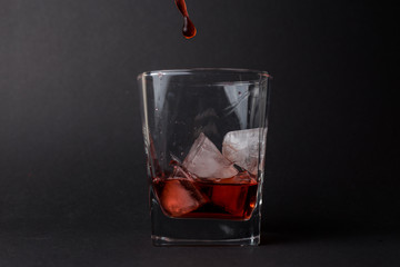 Vaso pequeño con hielo y whiskey en un fondo negro