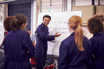 Male Tutor By Whiteboard With Students Teaching Auto Mechanic Apprenticeship At College