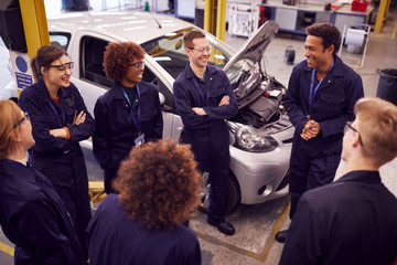 Male Tutor With Students Teaching Auto Mechanic Apprenticeship At College