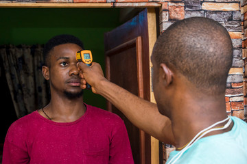 young african man having his body temperature checked with an infrared thermometer