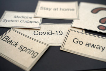 COVID-19, Go away, Black spring, Stay at home, medicine system collapse, printed on kraft paper. Coronavirus concept on black notepad