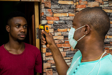 young african man having his body temperature checked with an infrared thermometer