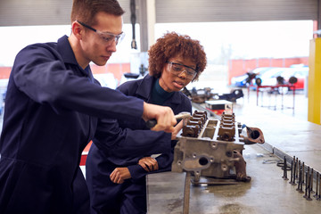 Male And Female Students Work On Car Engine Block On Auto Mechanic Apprenticeship Course At College