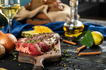 Raw meat on a wooden board with herbs and spices,lemon and vegetables