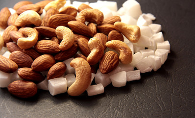 Cashews and almonds on pieces of coconut. Nuts on a black background.