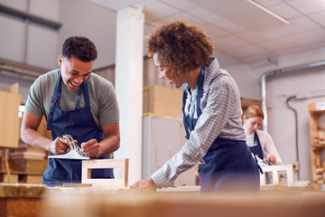 Female Tutor With Carpentry Student In Workshop Studying For Apprenticeship At College