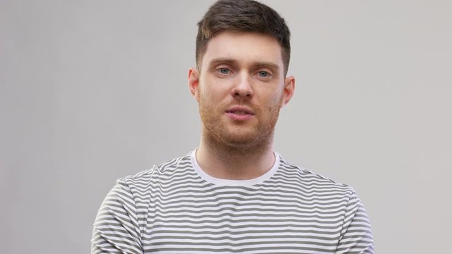 video blogging, communication and people concept - young man in striped t-shirt talking over grey background