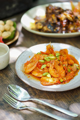 Sweet and sour prawns served on a ceramic plate. The green seeds on top are Petai or Parkia speciosa.