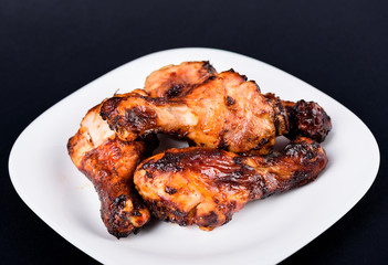 Dark background. Juicy grilled chicken drumsticks marinated in soy sauce.