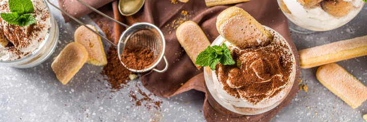 Traditional italian dessert tiramisu. Many glasses with homemade tiramisu with chocolate cocoa...