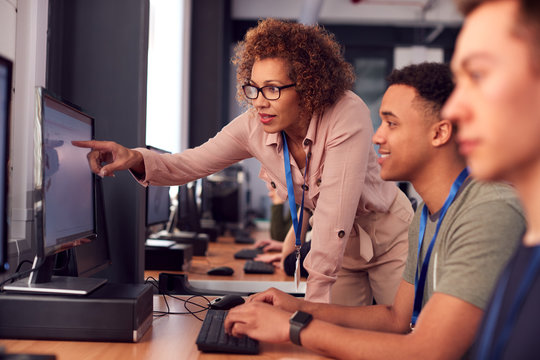 Group Of College Students With Tutor Studying Computer Design Sitting At Monitors In Classroom