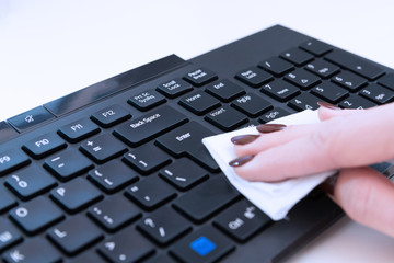 Female hand cleans the keyboard with a napkin with antibacterial gel