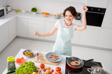 Photo of beautiful cheerful housewife lady peel boiled shrimps cooking and dancing excited prepared ingredients healthy food wear apron modern kitchen indoors