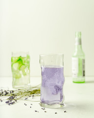 Two glasses of summer refreshing drinks, lavender lemonade and cucumber infused water, and empty bottle