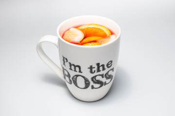Slices of lemon, lime, orange and grapefruit in a mug. Tea from multiple fruits in a cup, on a white background.