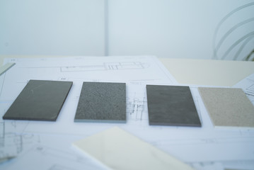 The interior designer selects ceramic stoneware and marble samples. Designer at work. Interior design. Architecture. Decoration. Design project blueprints. Grey marble. Grey stone. Decorative material