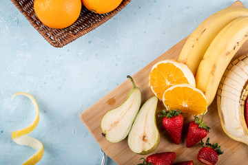 Banana, sliced pear,strawberries and oranges on a wooden board