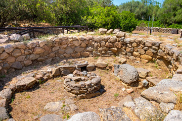 Arzachena, Sardinia, Italy - Archeological ruins of Nuragic complex La Prisgiona - Nuraghe La Prisgiona - with remaining of rounded stone meeting hut of Neolithic village