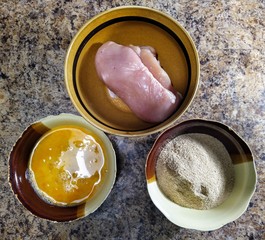 ingredients for chicken nuggets in bowls on table