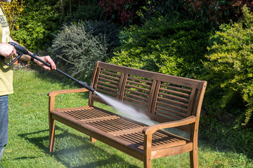 Man cleaning wooden bench with a high pressure cleaner