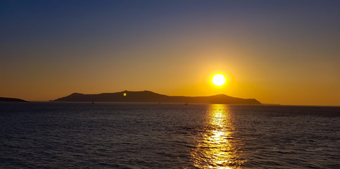 Naklejka na ściany i meble Suggestivo tramonto a Santorini, tra un sole caldo e profondo, un mare da sogno ed un clima appagante
