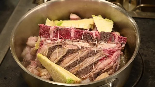 Cuisson d'un carr&eacute; de veau avec l&eacute;gumes dans une cocotte en inox dans un restaurant