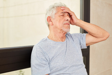 Senior Mann fasst sich erschöpft an den Kopf